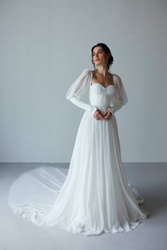 a woman in a white wedding dress standing on a white floor with her arms behind her back