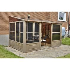 an enclosed patio with sliding glass doors on the side and brick building in the background