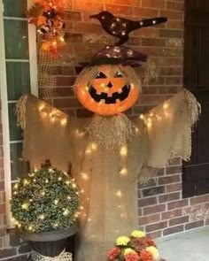 a scarecrow is standing next to a potted plant with a pumpkin on it