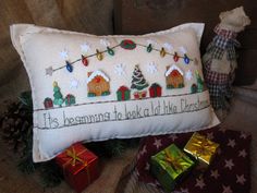 a decorative pillow with christmas decorations and presents on the side, along with a teddy bear