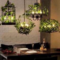 a dining room table with some plants hanging from it's ceiling and plates on the table