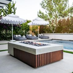 an outdoor fire pit with umbrellas over it