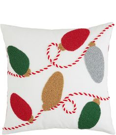 a white pillow with christmas ornaments on it and red, green, and gold trimmings