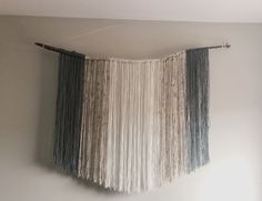 a wall hanging made out of yarn and wood sticks in a room with white walls