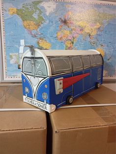 a blue and white bus sitting on top of boxes in front of a world map