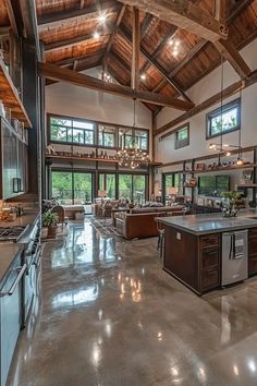 a large open concept kitchen and living room with wood beams on the ceiling, high ceilings, and glass windows