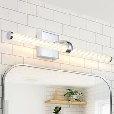 a bathroom vanity with a mirror and light above it on the wall next to a potted plant