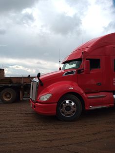 a red semi truck is parked in the dirt