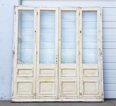 an old white double door on the side of a building in front of a garage