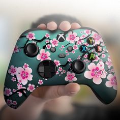 a person holding a controller in their hand with flowers painted on the front and sides