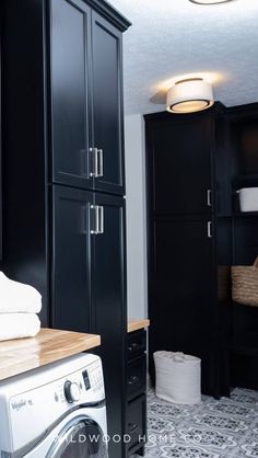 a washer and dryer in a small room with black cabinetry, wood counter tops and flooring