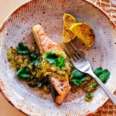 a white plate topped with fish covered in sauce and garnished with cilantro