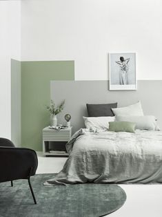 an image of a bedroom setting with green and white colors on the walls, black chair in foreground