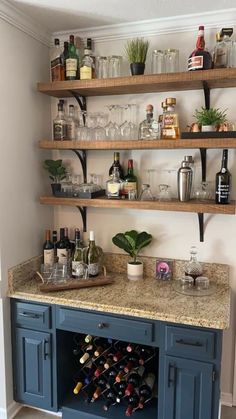 a kitchen with blue cabinets and shelves filled with wine glasses, liquor bottles and plants