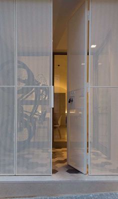 an open door to a room with a bike on the wall and white mesh covering it