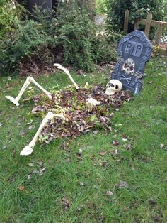 a skeleton laying in the grass next to a grave with plants growing out of it