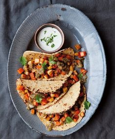 three tacos on a plate with a small bowl of ranch dressing