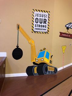 a construction themed wall in a child's room with toys on the floor and a sign that says jesus our strong foundation