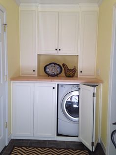 a washer and dryer in a small room with yellow walls, black and white chevron rug