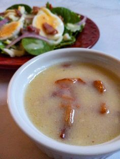 a bowl of soup next to a plate with salad on it