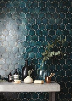 a table with vases and other items on it in front of a tiled wall