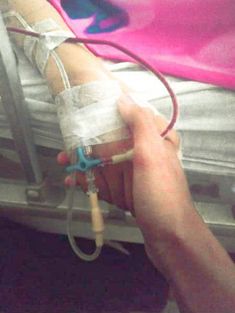 someone is holding an iv device in their hand and it's attached to the back of a bed