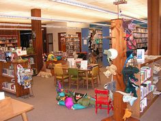 a library filled with lots of books and stuffed animals sitting on the floor next to each other