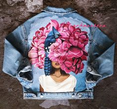 a jean jacket with a woman's face painted on it and flowers in the back