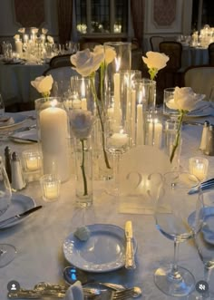 the table is set with candles, plates and silverware for an elegant wedding reception