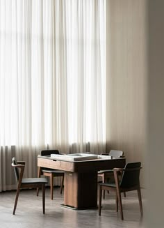 a table and chairs in front of a window with white drapes on the windowsill