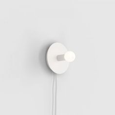 a white wall mounted light on the side of a wall with a cord attached to it