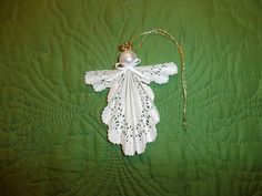 a white angel ornament on a green quilted bed with a beaded string