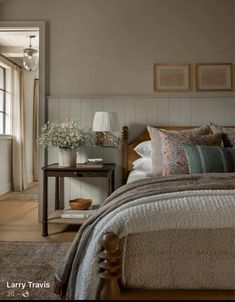 a large bed sitting next to a window with pictures on the wall above it in a bedroom