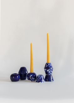 three blue candles sitting next to each other on top of a white surface with one yellow candle in the middle