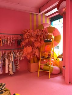 a pink and yellow room with clothes hanging on the rack