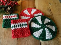 three crocheted christmas coasters sitting on top of a wooden table