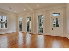 an empty living room with wood floors and french doors leading to the front door is shown