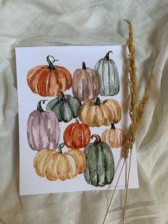 a card with watercolor pumpkins on it and wheat stalks in the foreground