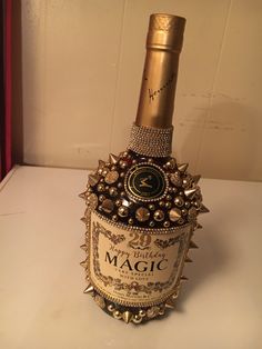 a bottle of wine that has been decorated with jewels and pearls on the top, sitting on a table