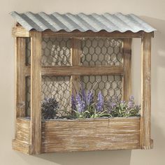 a wooden window box with plants in it and a chicken wire fence around the top