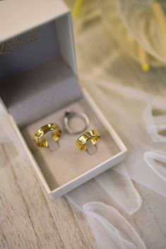 two gold rings sitting in a white box