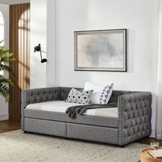 a living room with a couch, coffee table and potted plant on the floor