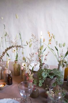 there are many vases with flowers in them on the table next to each other