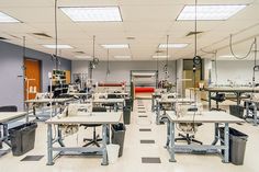 a room filled with lots of desks and chairs next to each other in front of windows