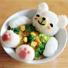 a small white bowl filled with food on top of a wooden table next to a teddy bear