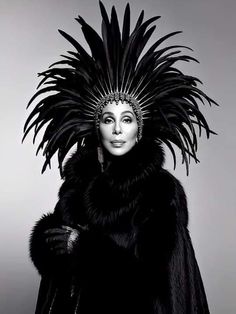 a woman wearing a black feather headdress with feathers on her head and fur coat