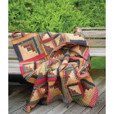 a quilted blanket sitting on top of a wooden bench