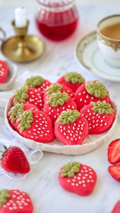 some strawberries are sitting on a plate next to cups and saucers