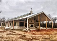 a house that is in the middle of some dirt and has a lot of windows