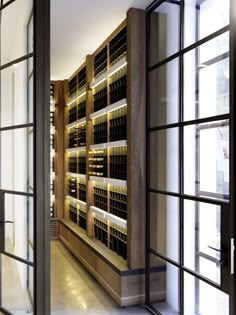 a wine cellar in the middle of a room with lots of glass doors and windows